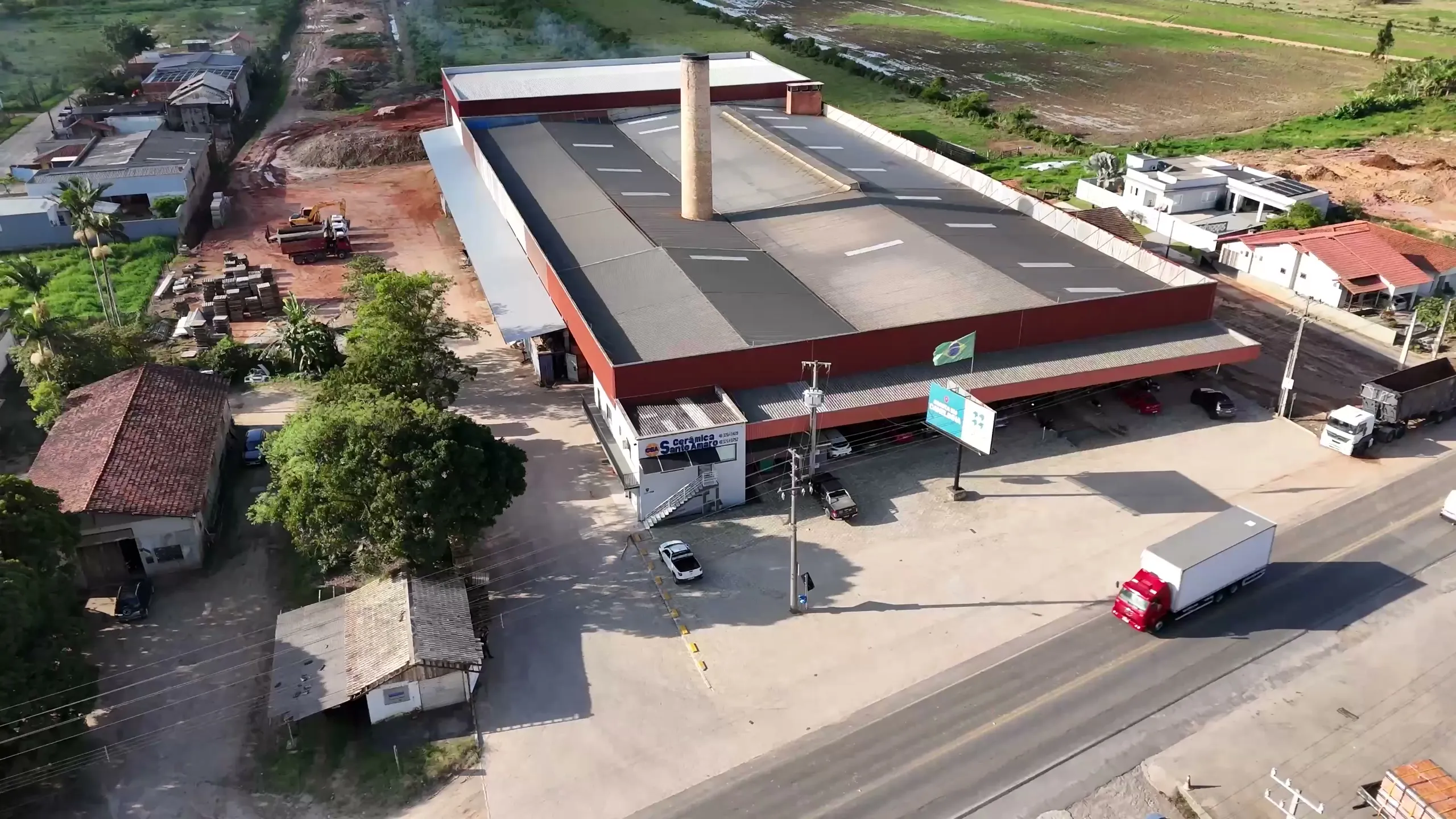 Vista aérea da fábrica na Rodovia SC-410, com a entrada, o pátio e um caminhão na pista